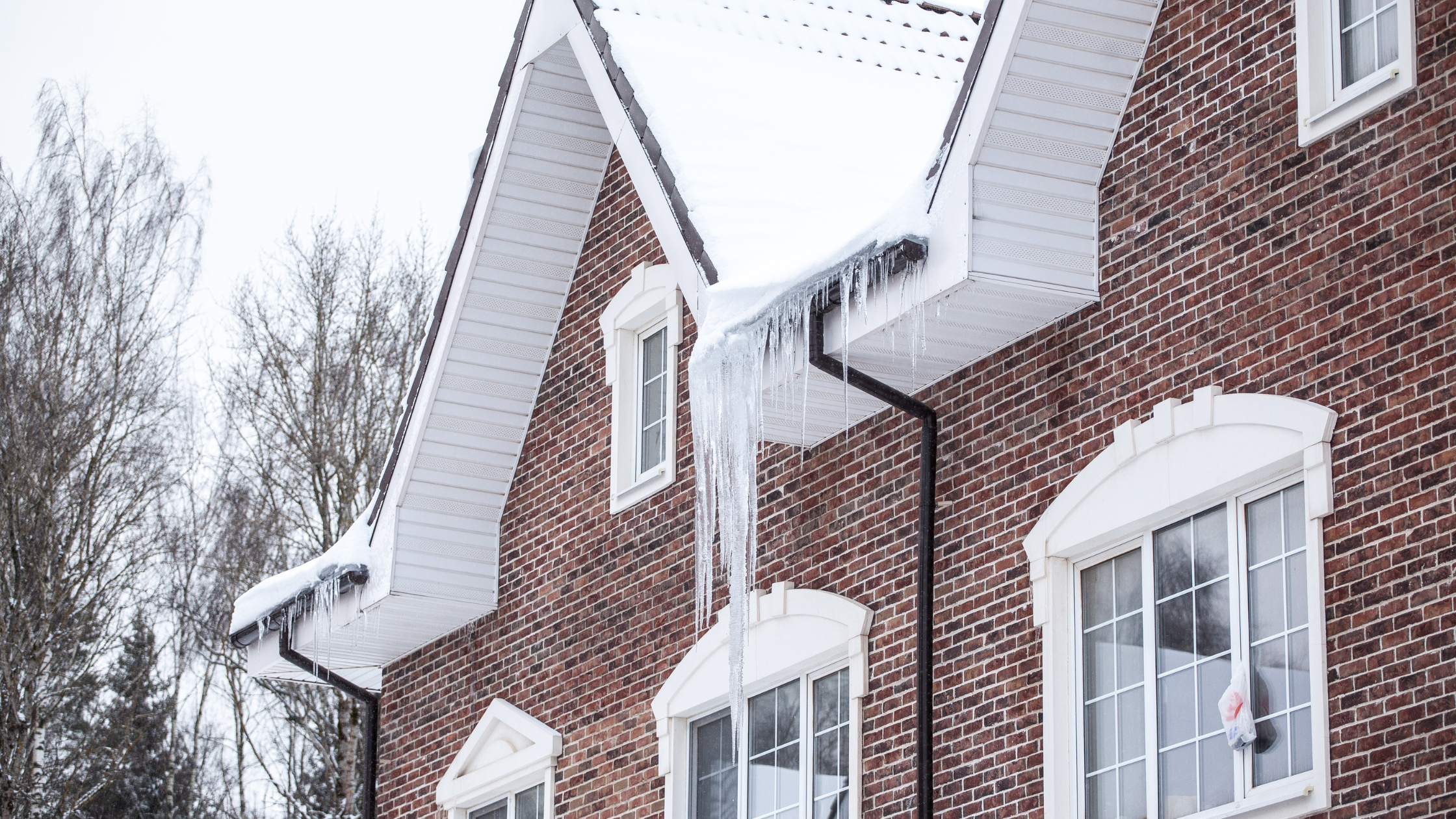 Ice dams hanging off of a brick house in winter
